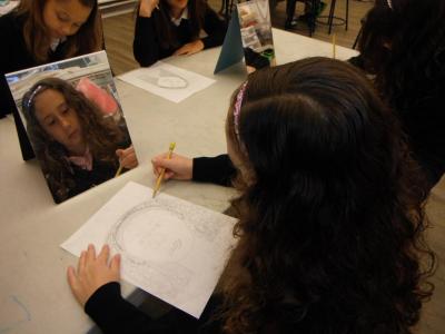 Female student drawing a self portrait in art class